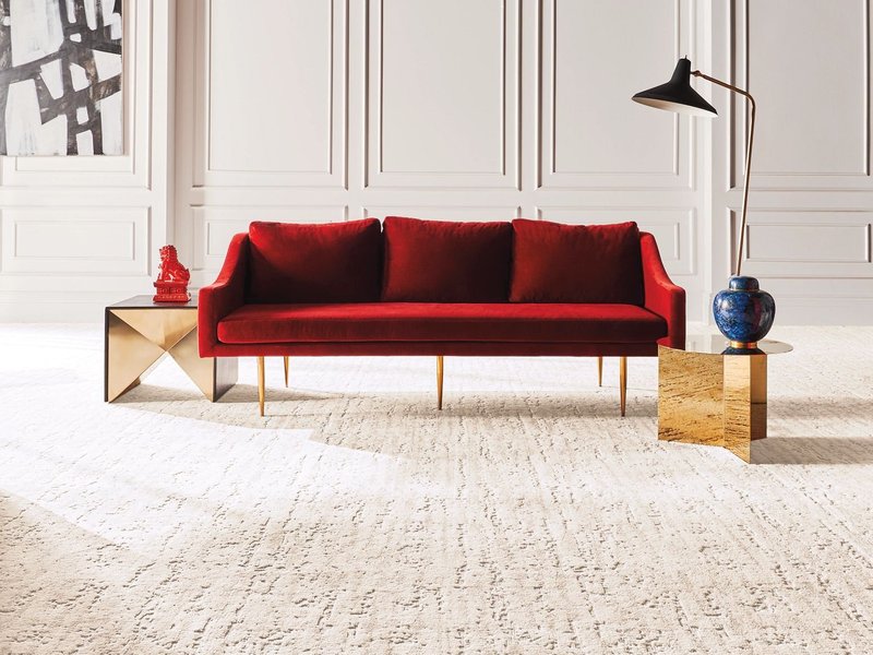 Bright living room with a red velvet couch and beige textured carpet from Northcraft Flooring & Design in Lee's Summit, MO