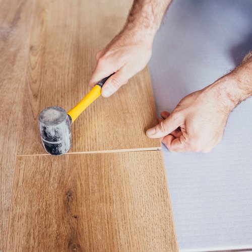 man with a hammer installing hardwood flooring from Northcraft Flooring & Design in Raytown, MO