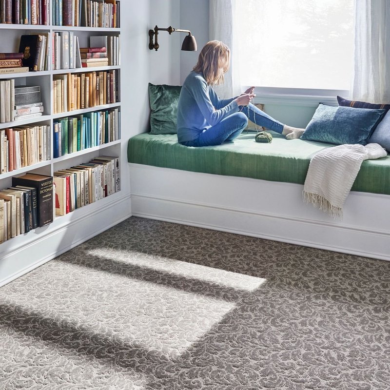 girl kitting on a bed in a room with gray patterned carpet from Northcraft Flooring & Design in Lee's Summit, MO